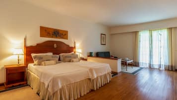 Une chambre d’hôtel avec un grand lit, des tables de chevet avec des lampes, un bureau et une chaise.