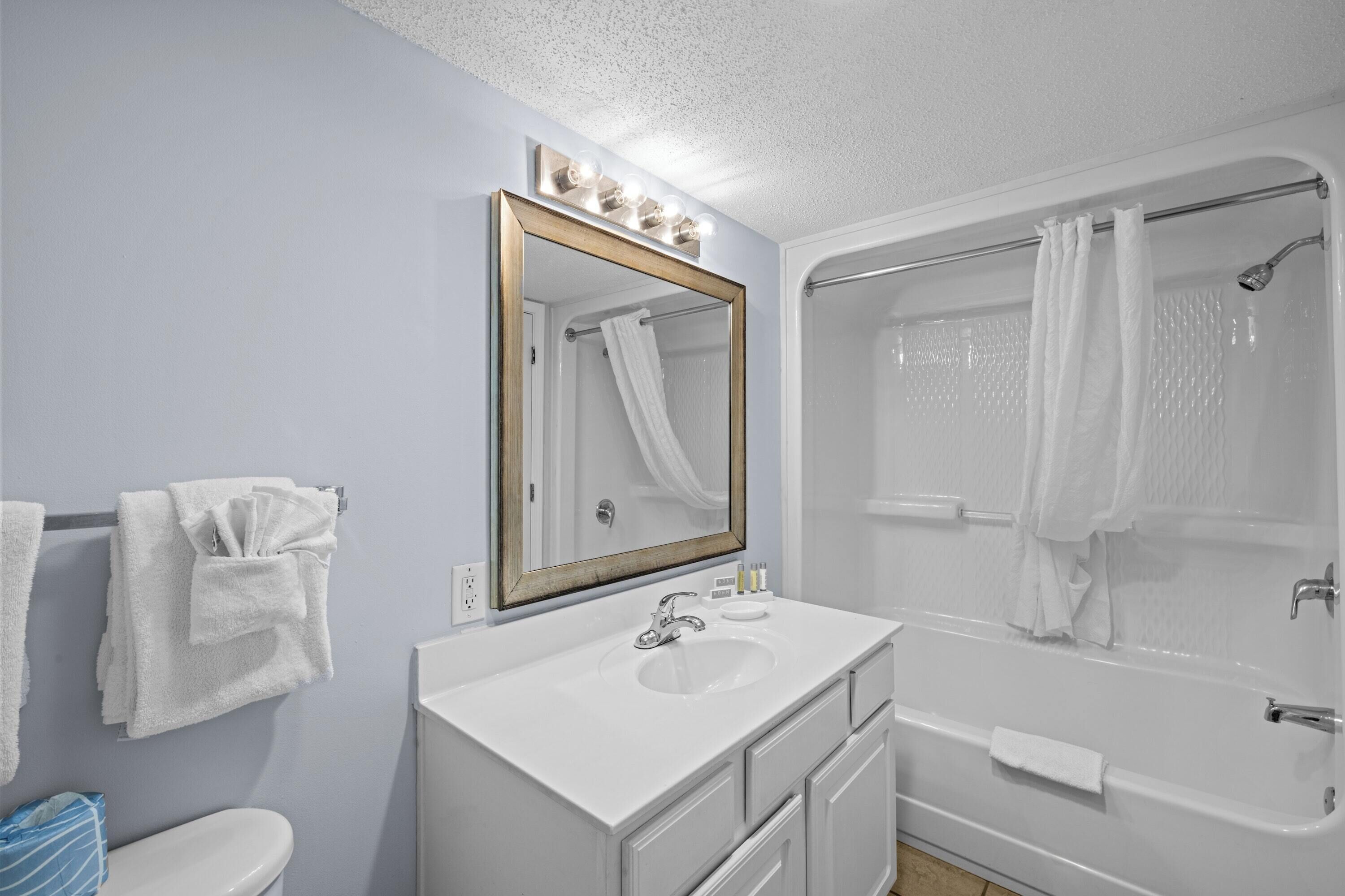 Un baño con lavamanos, espejo y bañera.