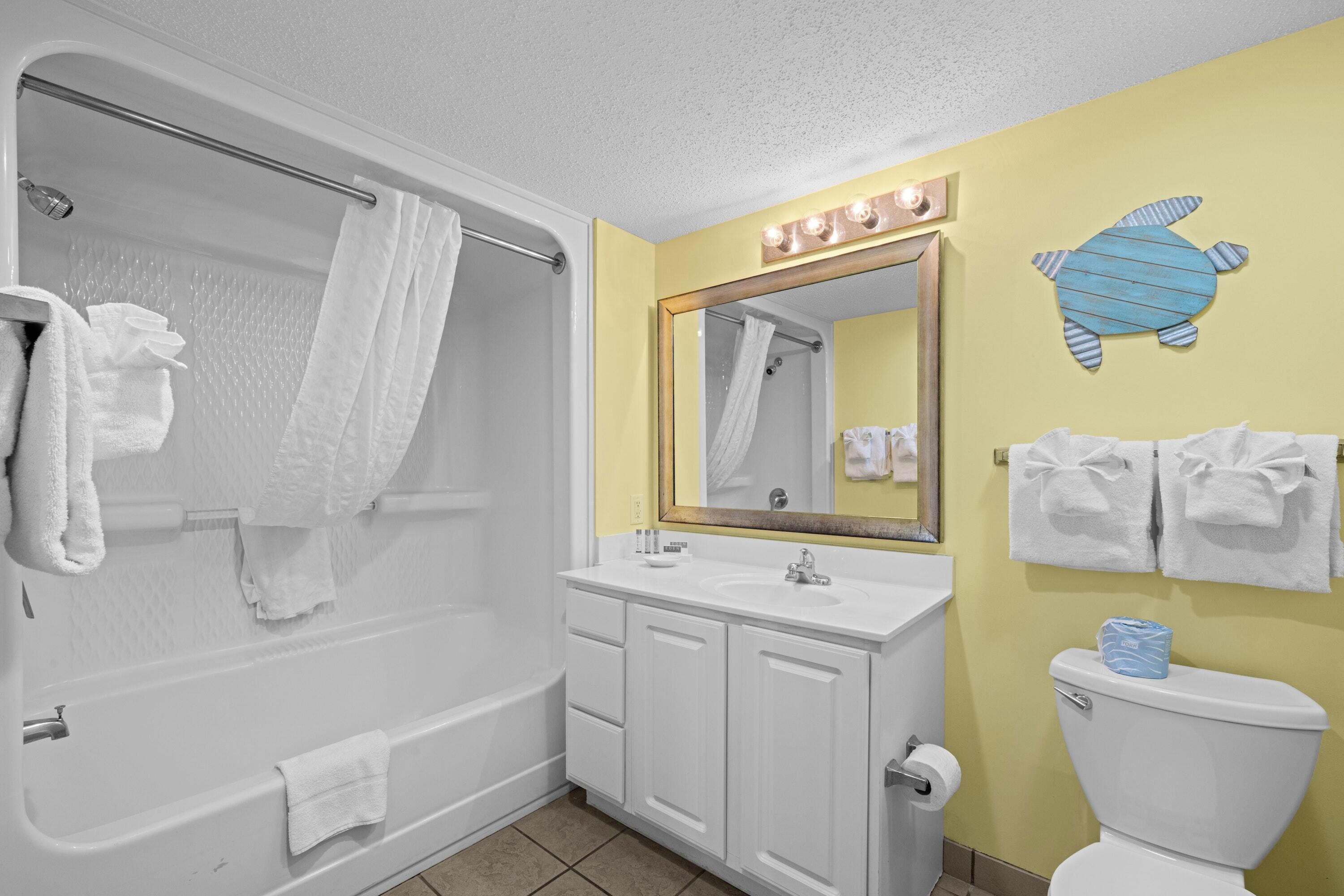 A bathroom with a bathtub, a sink, a toilet, and a mirror with lights.