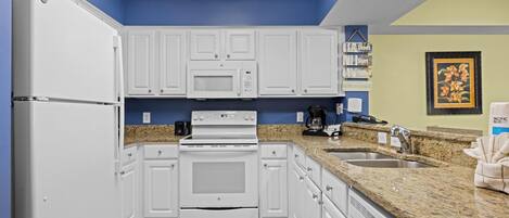 A kitchen with white cabinets, a microwave, an oven, a sink, and granite countertops.