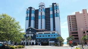 A multi-story hotel with a prominent 'Paradise' sign, a central entrance, and a view of the ocean.