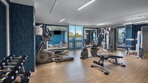 A modern gym with cardio equipment, weight machines, and a mirror wall.