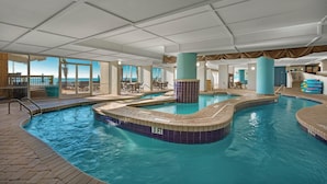An indoor swimming pool with a 3 FT depth marker, surrounded by lounge areas and large windows offering views.