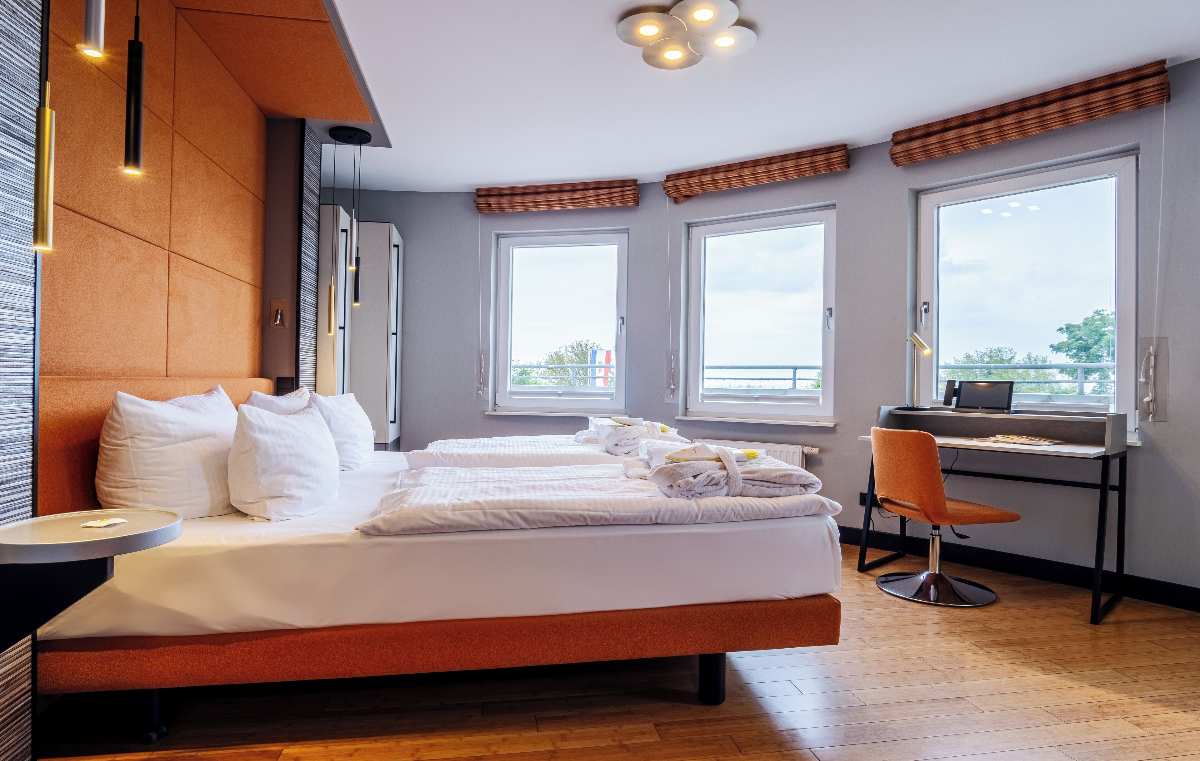 Ein modernes Hotelzimmer mit einem großen Bett, einem Schreibtisch und großen Fenstern.
