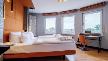 Et moderne hotelværelse med en stor seng, et skrivebord og store vinduer.