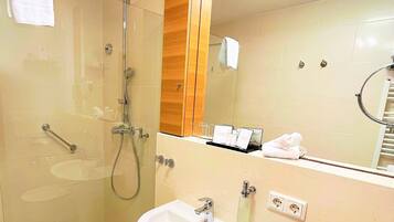 A modern bathroom with a glass-enclosed shower, a white sink, and a mirror with a wooden cabinet above it.