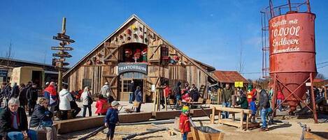 Un bâtiment en bois sur lequel est apposée une enseigne indiquant « TRAKTORBAHN » et un grand silo rouge portant l’inscription « Erdbeer Moste ».