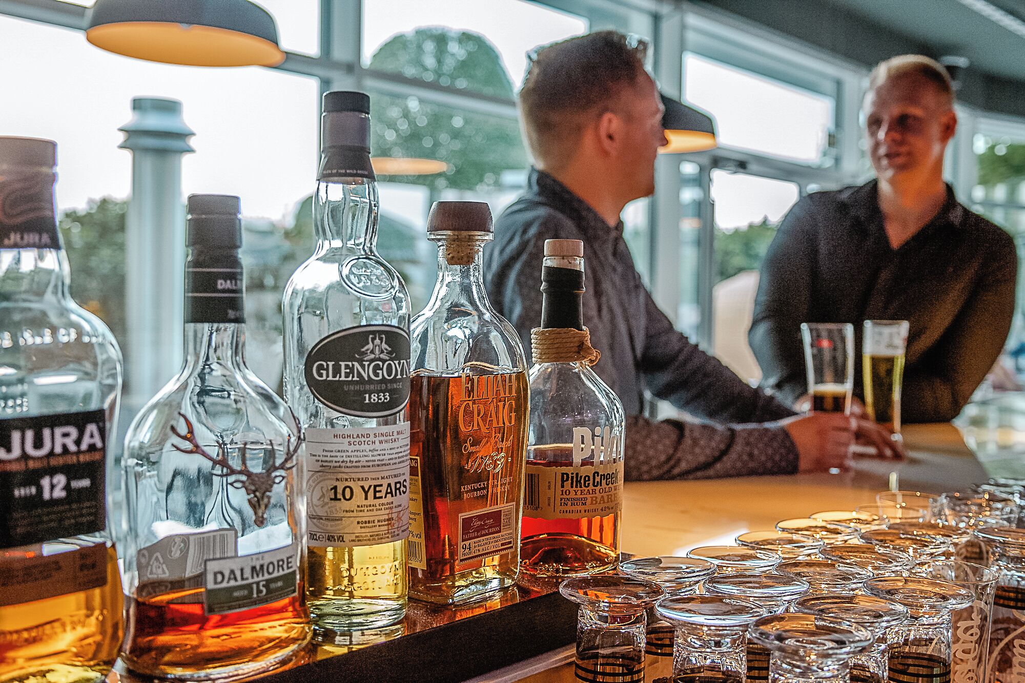 A bar with various bottles of whisky and glasses.