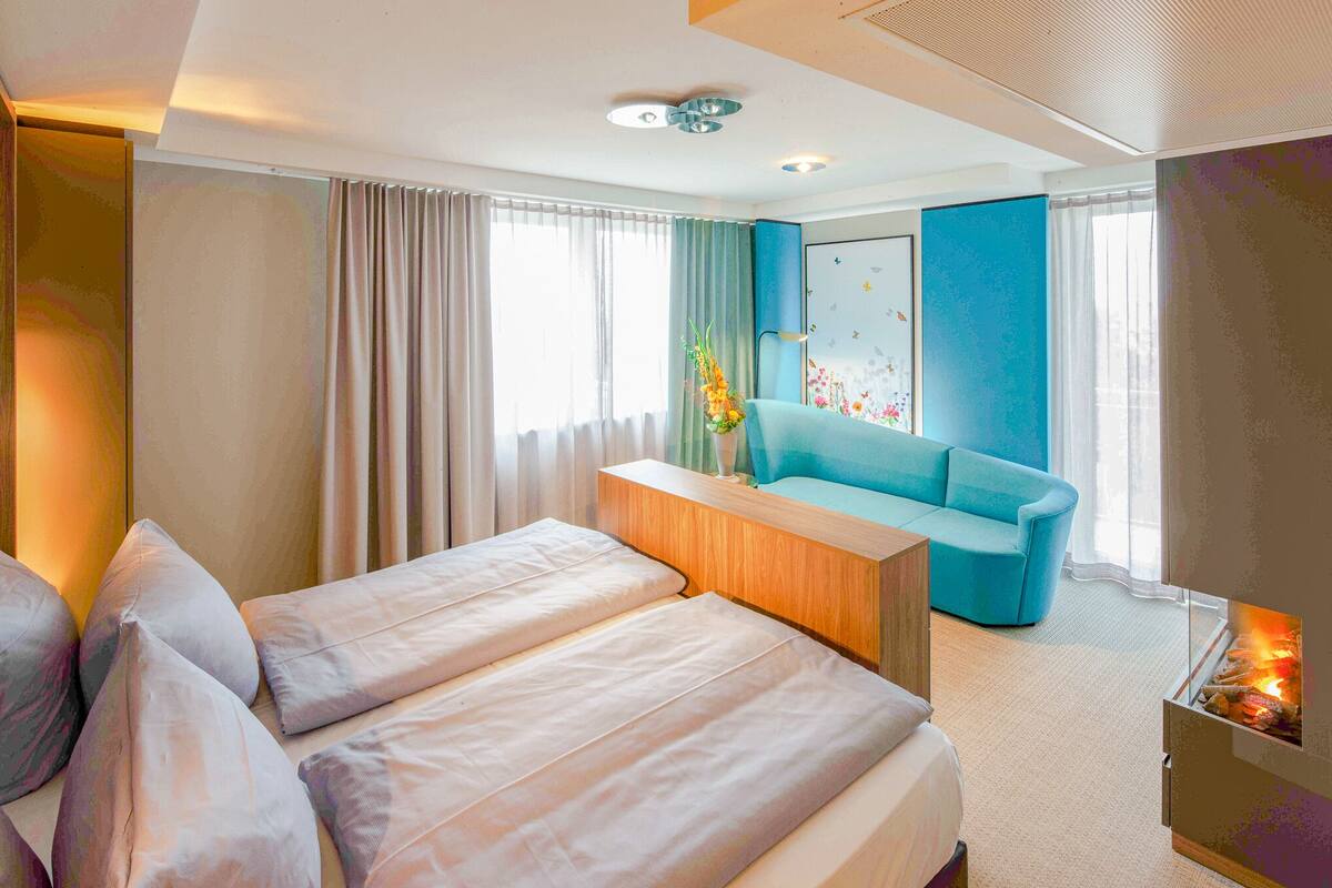 Une chambre d’hôtel moderne équipée d’un lit, d’un canapé, d’une table d’appoint en bois et d’une cheminée.