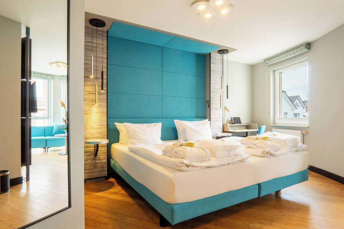Une chambre d’hôtel moderne avec un grand lit, une vue sur la ville et un petit bureau avec une chaise.