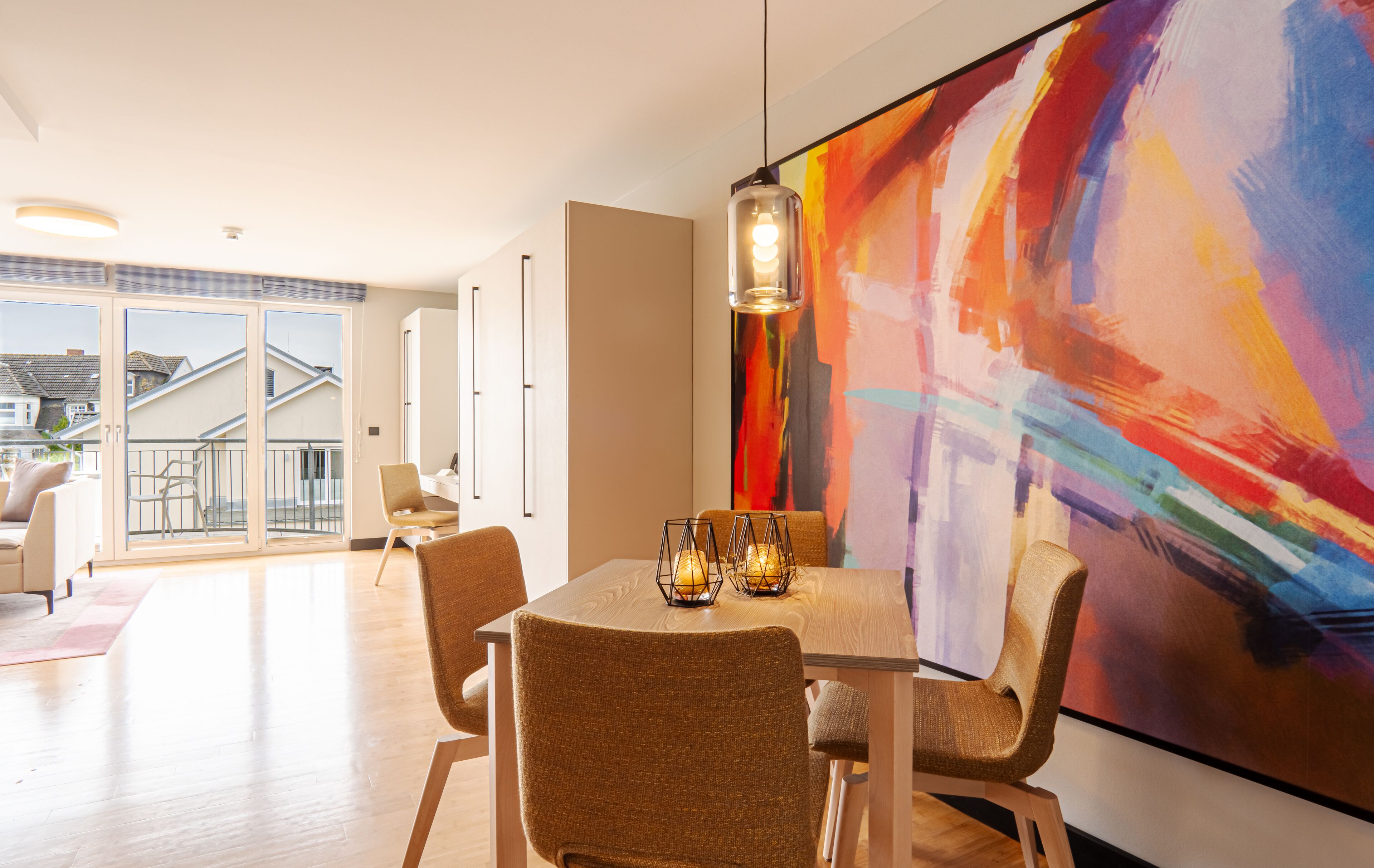 Un comedor moderno con un cuadro abstracto de gran tamaño, muebles de madera y vistas al exterior.