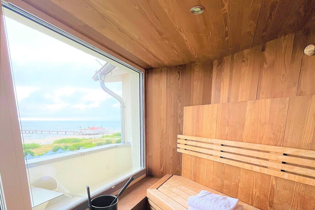 Un sauna en bois, avec un banc et une fenêtre donnant sur une plage.