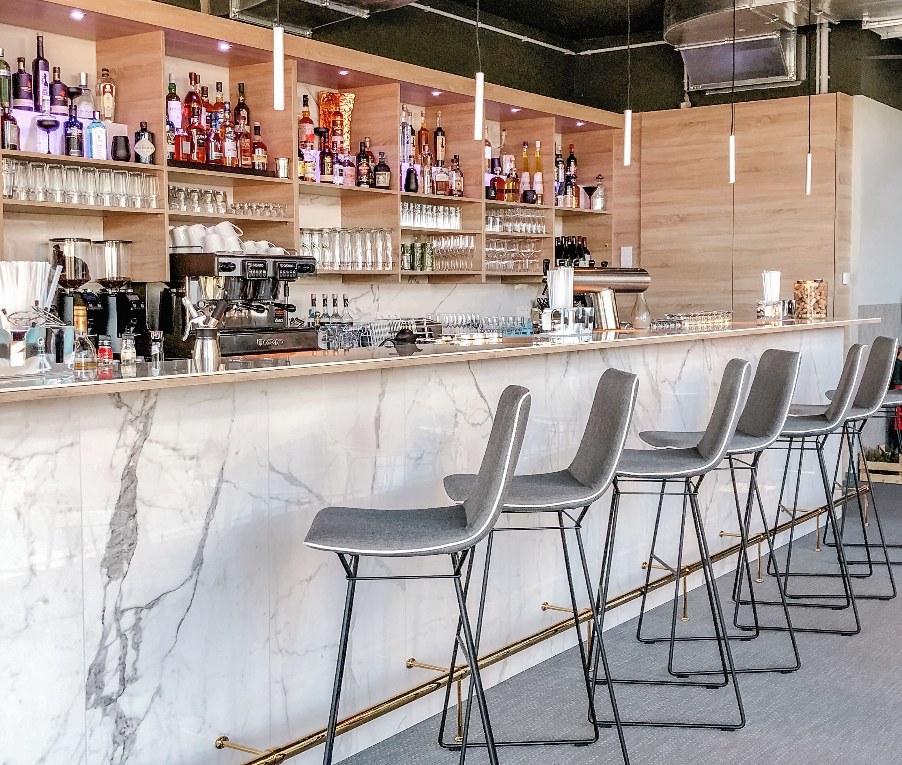 A bar area with marble countertops, multiple shelves of liquor bottles, and bar stools.