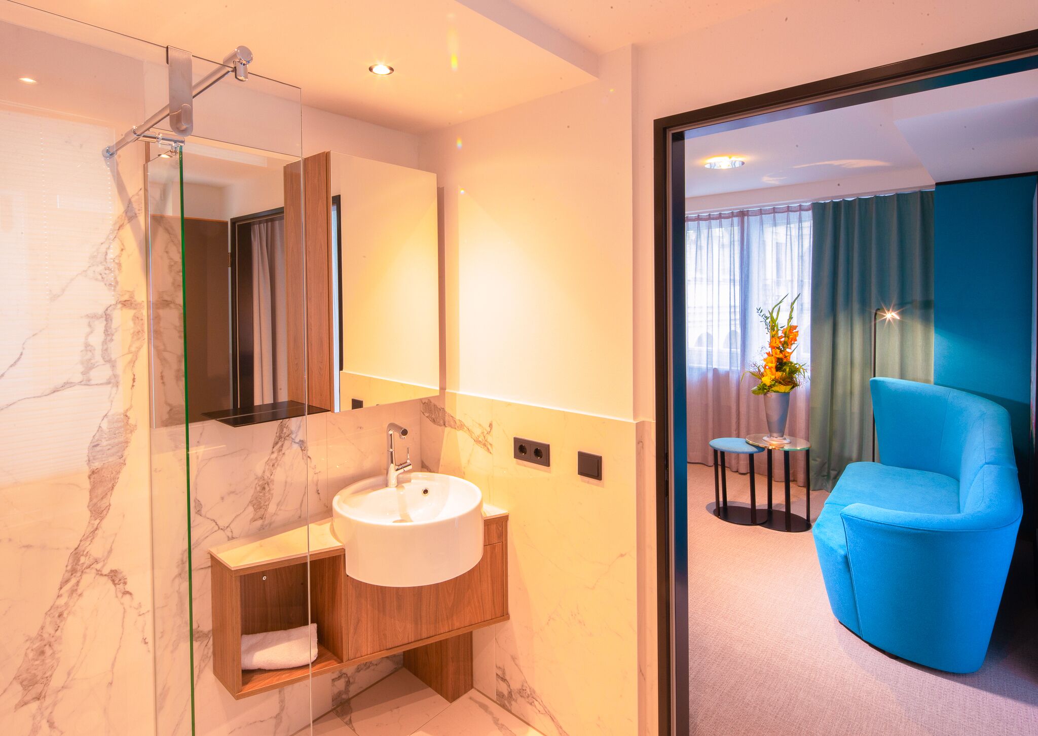 Une salle de bain moderne avec un lavabo en marbre, une cabine de douche en verre et un meuble-lavabo en bois.