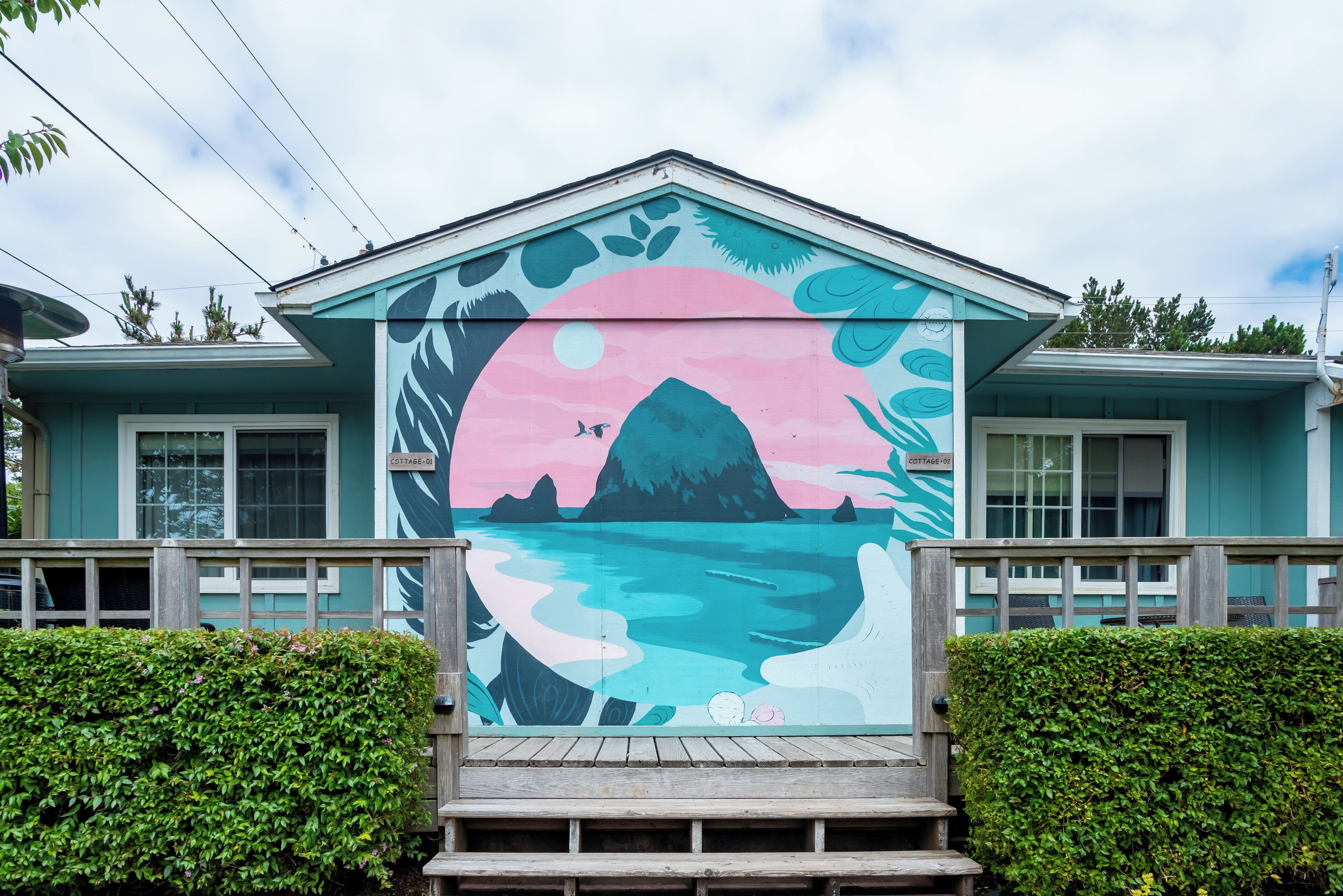 A building with a colorful mural of a landscape, a wooden deck, and a sign reading "Cottage 18".