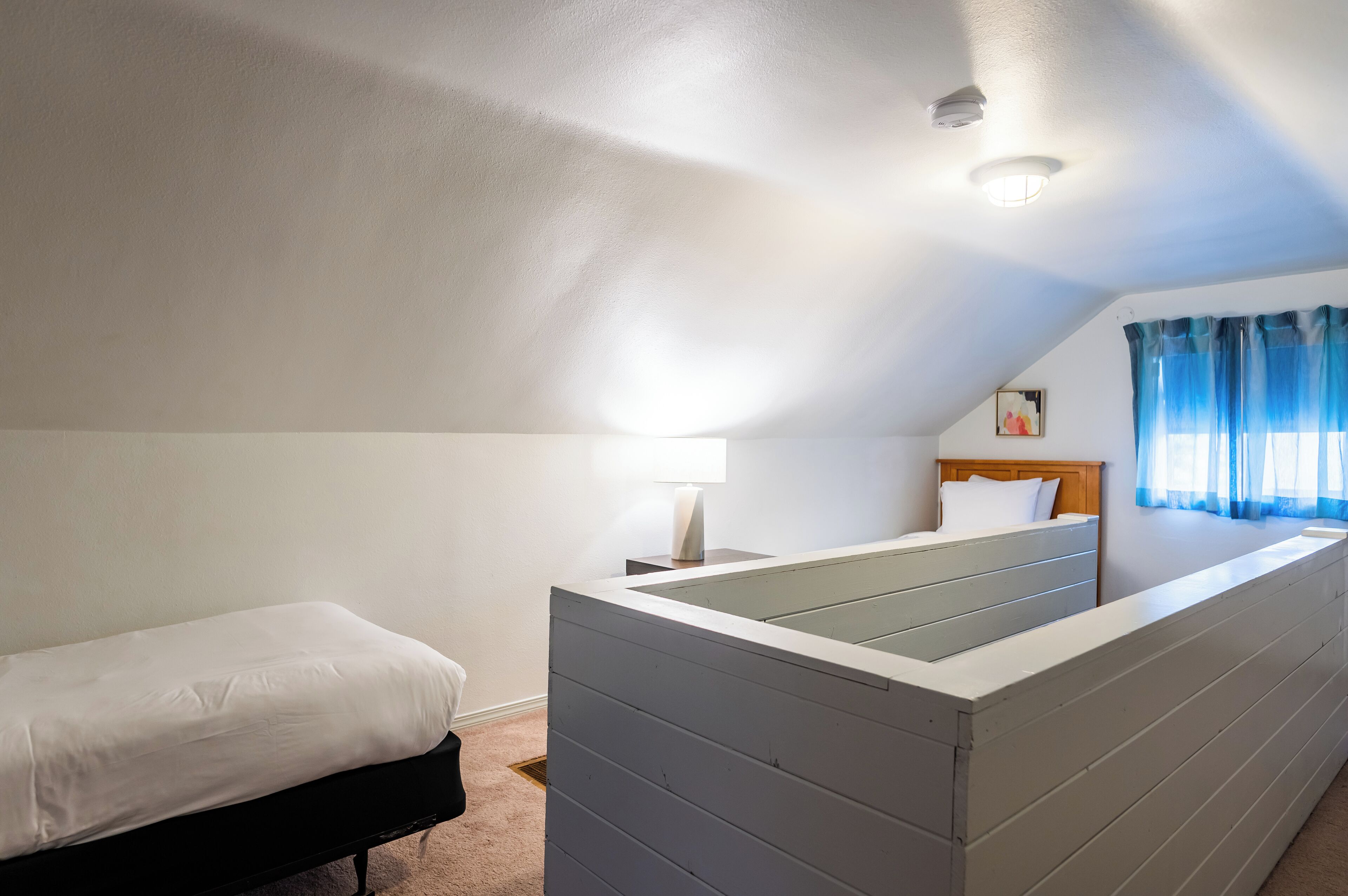 Una camera da letto con un letto, un comodino con una lampada, una cassettiera e una finestra con tende.