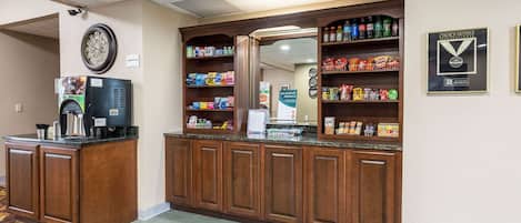 A reception area with a coffee machine, a clock, and shelves stocked with snacks and beverages.