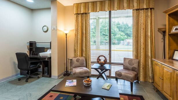 A room with a desk, two armchairs, a coffee table, a lamp, a clock, and a window with curtains. - Quality Inn Heber Springs (Heber Springs)
