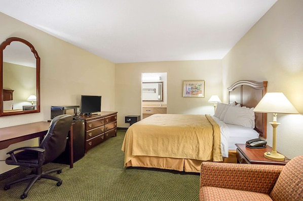 A hotel room with a bed, desk, chair, and a mirror.