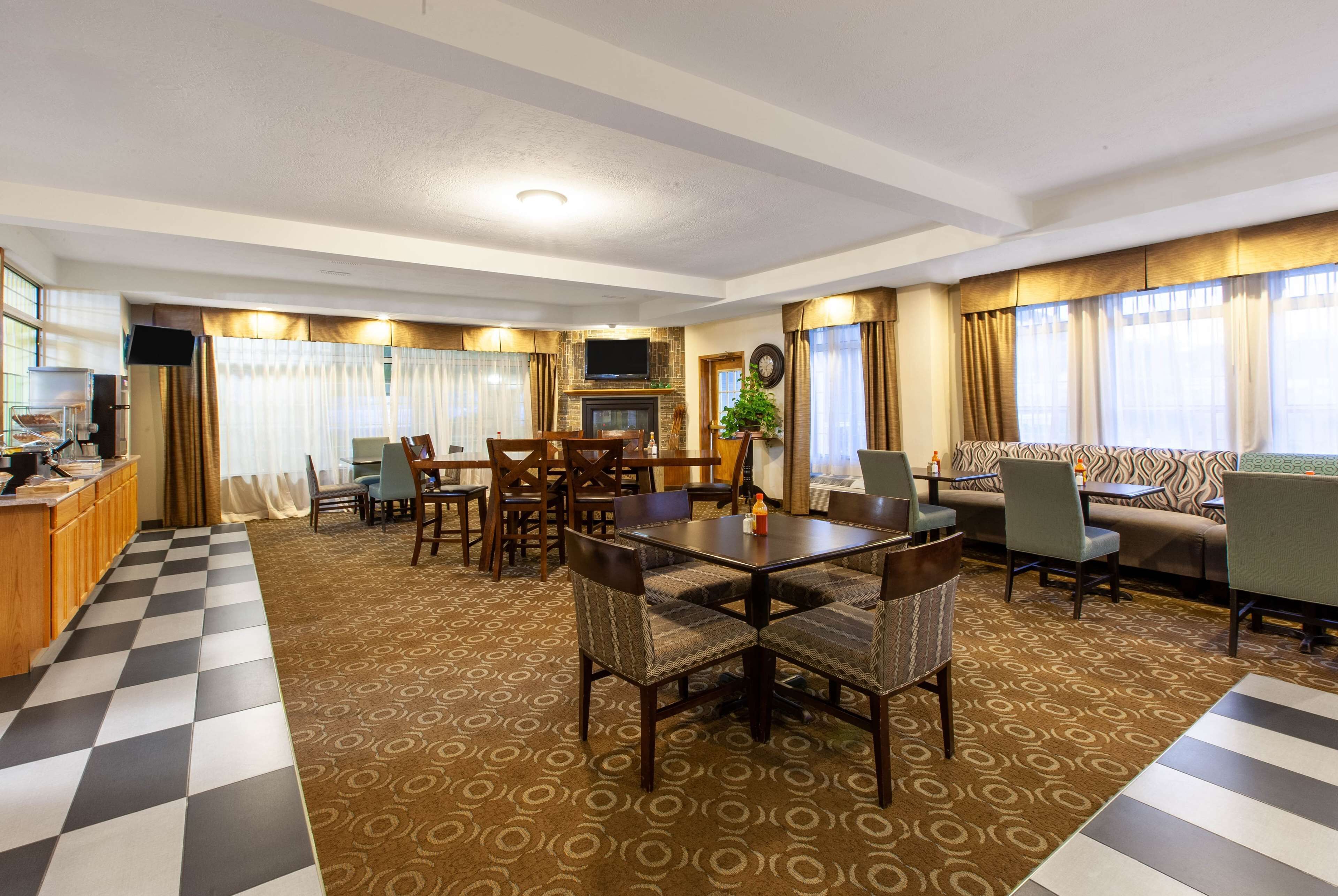 Una habitación de hotel con piso a cuadros, una zona de comedor con mesa y sillas, un sofá y un televisor.