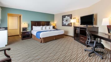 A hotel room with a large bed, a desk with a computer, a television, and two bedside lamps.
