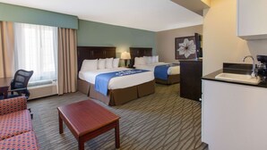 A hotel room with a bed, a desk, a chair, a small table, and a kitchenette. - Days Inn by Wyndham Petoskey (Petoskey)