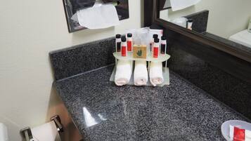 Ein Badezimmer mit Marmorplatte, einem Spiegel und Pflegeprodukten, darunter Flaschen und eine Schachtel mit dem Aufdruck "SPA Green".