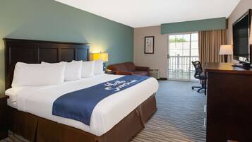 A hotel room with a large bed, a desk with a computer, a chair, and a television.