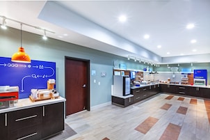 Un moderno vestíbulo de hotel con una recepción, una estación de café y una vitrina de comida.