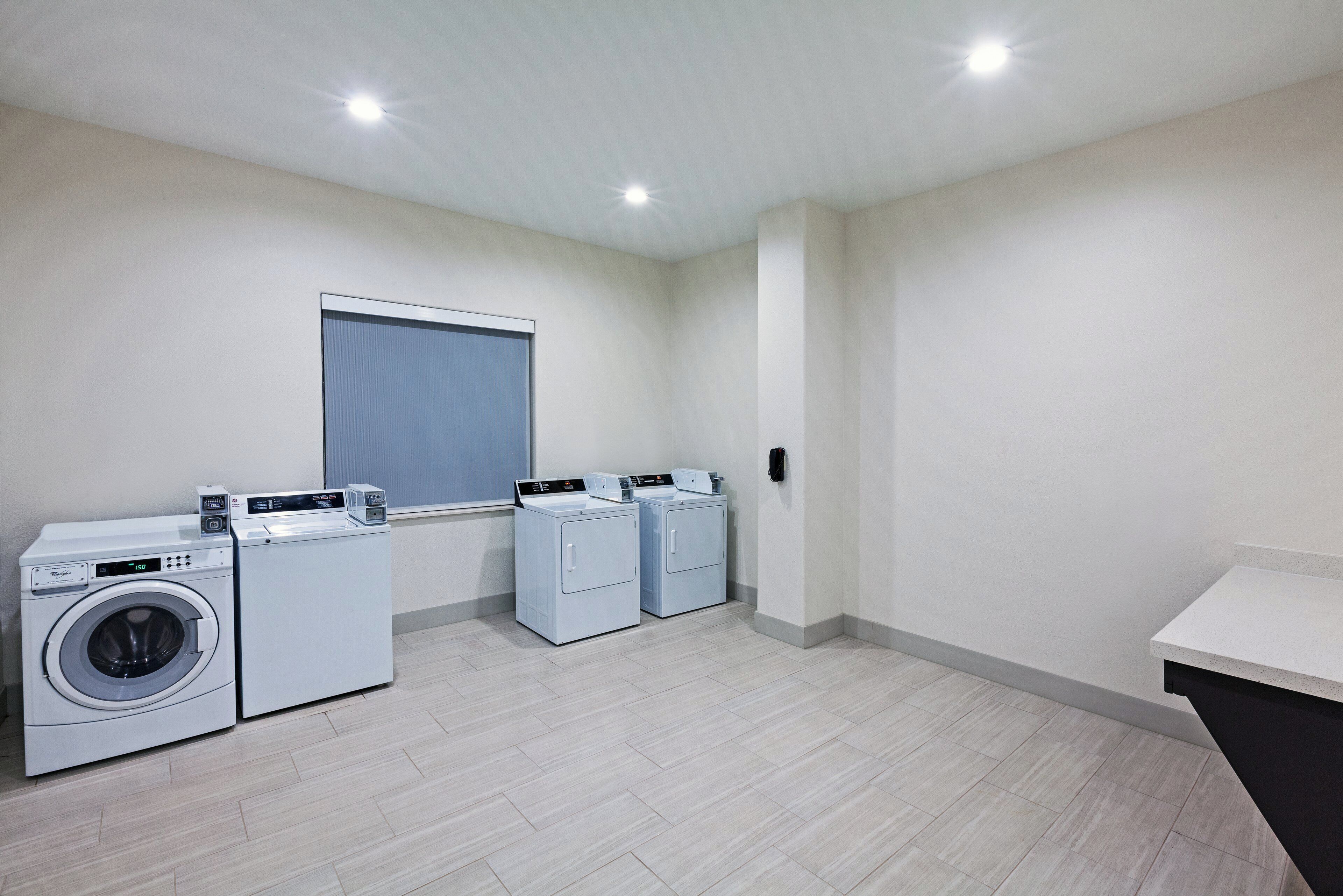 A laundry room with a front-loading washing machine, a dryer, and a folding station.