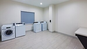 A laundry room with a front-loading washing machine, a dryer, and a folding station.
