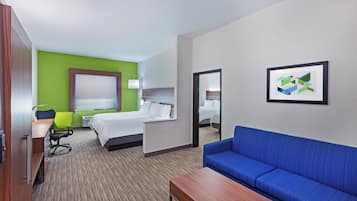 Habitación de hotel con cama, sofá azul, escritorio, silla y un cuadro en la pared.