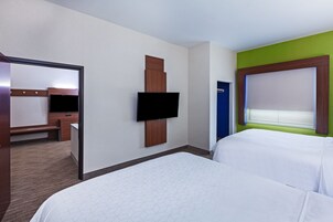 Una habitación de hotel con una cama grande, un televisor de pantalla plana en la pared, un escritorio con una silla y una puerta con marco azul.