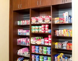 A pantry with shelves stocked with various food items including cereals, canned goods, and snacks.