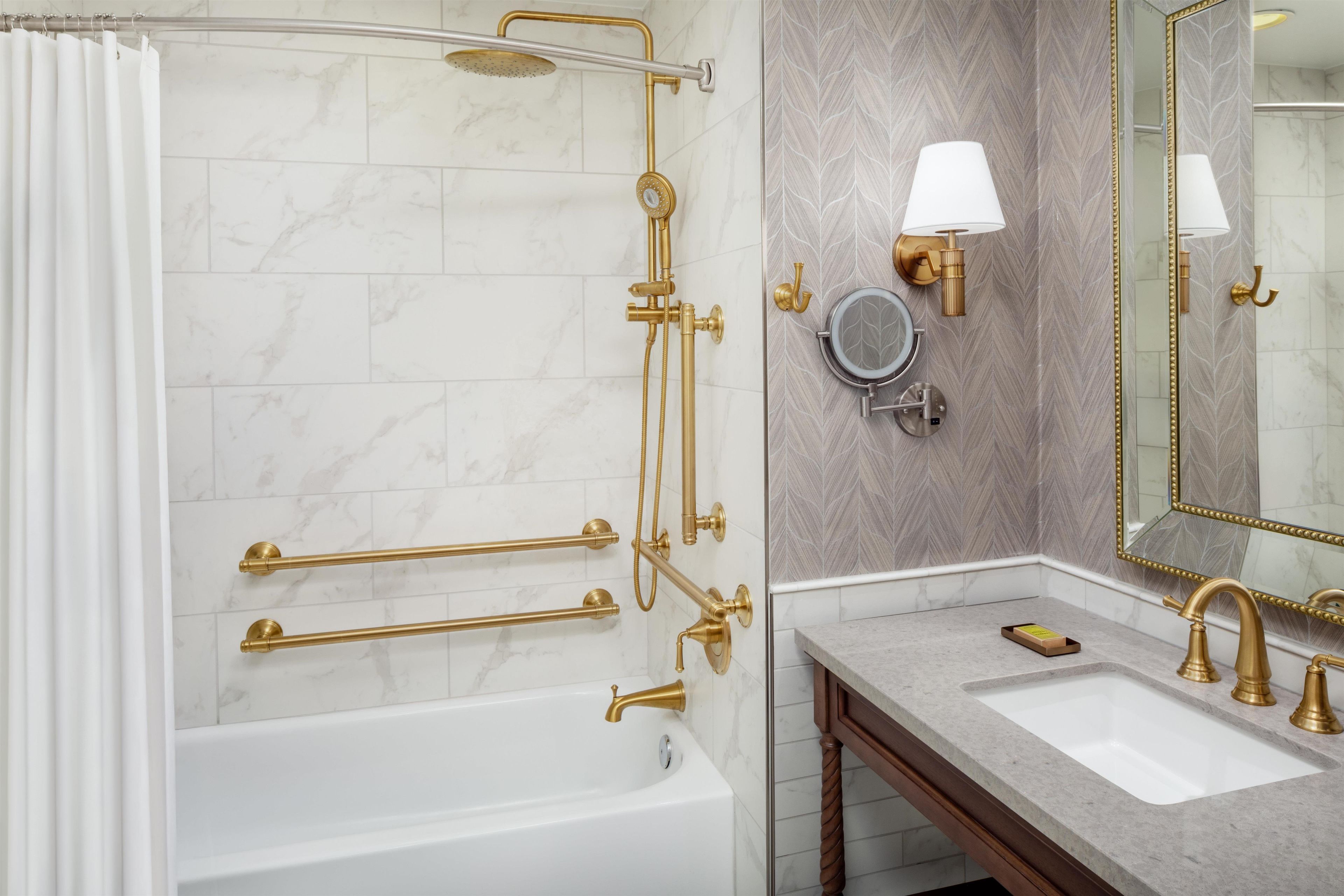 A bathroom with a bathtub, a shower, a vanity with a sink, and a mirror.