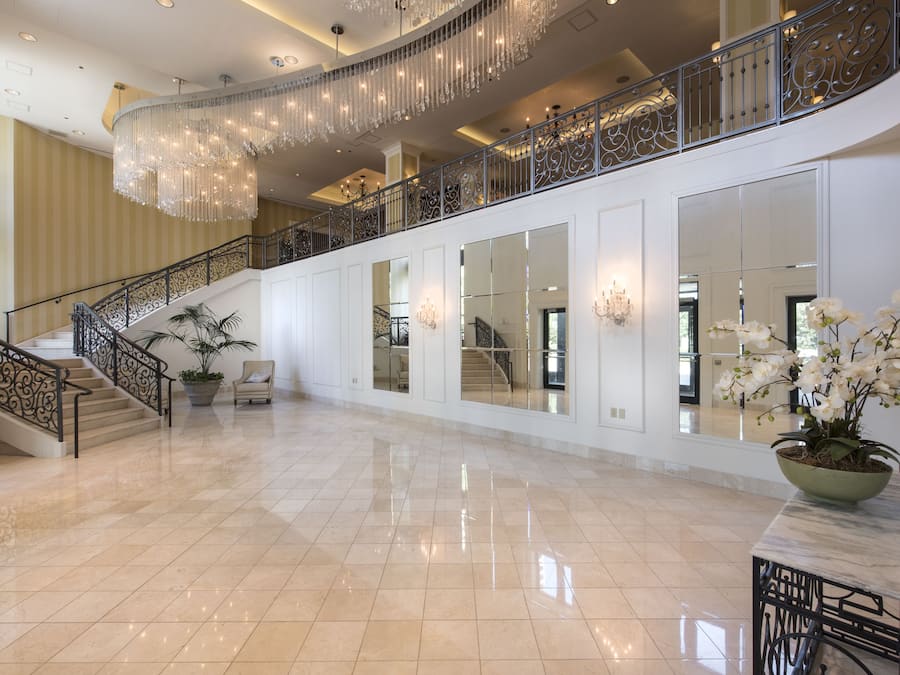 Eine geräumige Lobby mit einer imposanten Treppe, einem Chandelier und einer Orchidee im Topf.