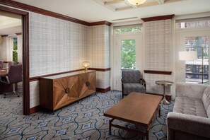 A hotel room with a wooden console table, patterned carpet, a sofa, and a chair. - Skirvin Oklahoma City, a Hilton Hotel (Oklahoma City)