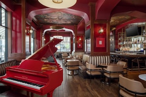 A red grand piano in a spacious room with a bar and seating area.