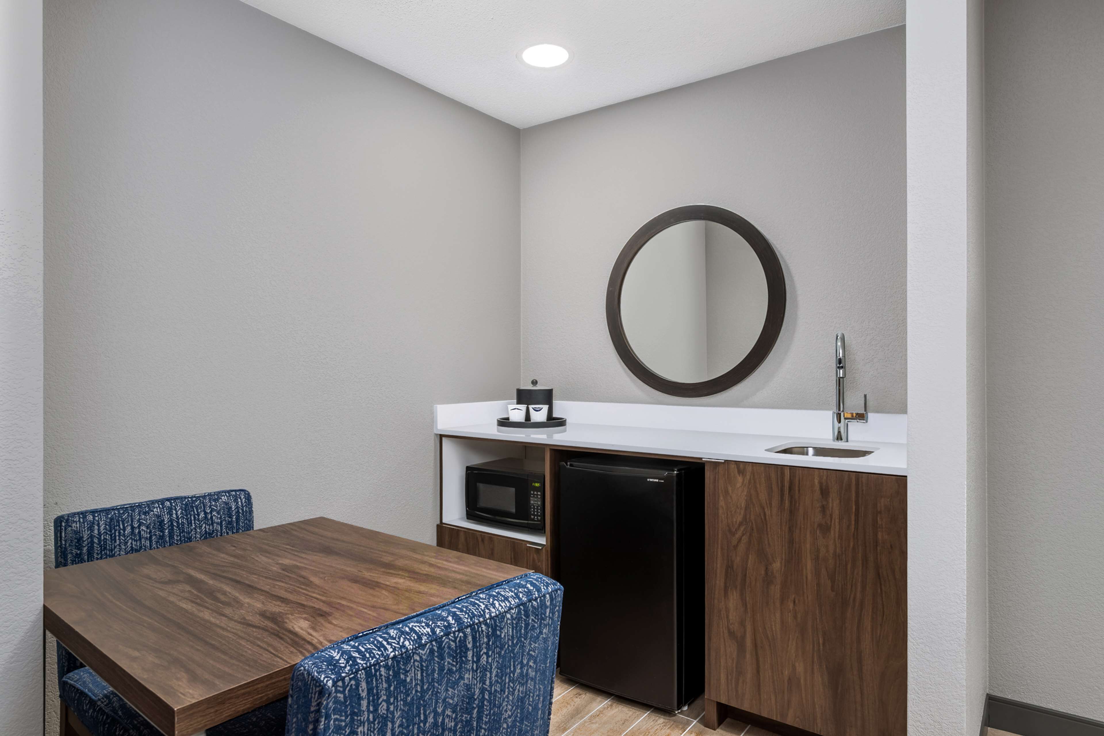 A compact kitchenette with a microwave, refrigerator, and sink.
