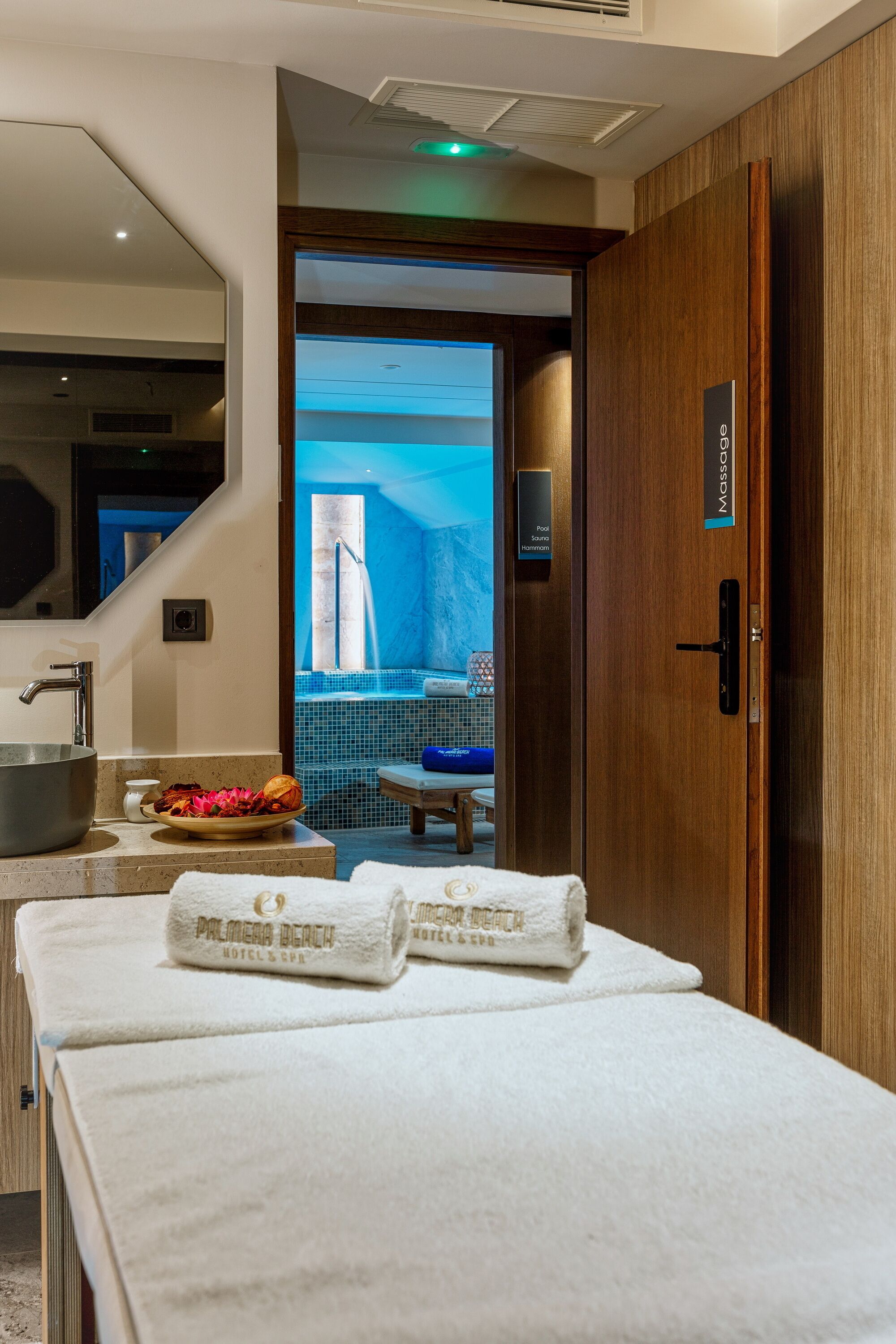 A hotel room with a massage area, a large sink, and a view of a pool and jacuzzi.