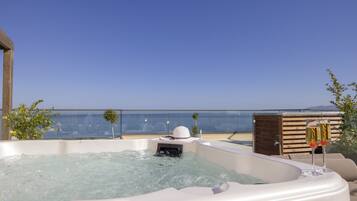 A hot tub with a clear view of the sea and a wooden deck.