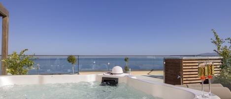 A hot tub with a clear view of the sea and a wooden deck.
