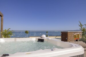 Un bain à remous avec une vue dégagée sur la mer et une terrasse en bois.