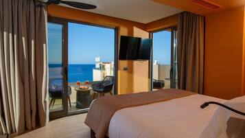 Quarto de hotel com cama, televisão e varanda com vista para o mar.