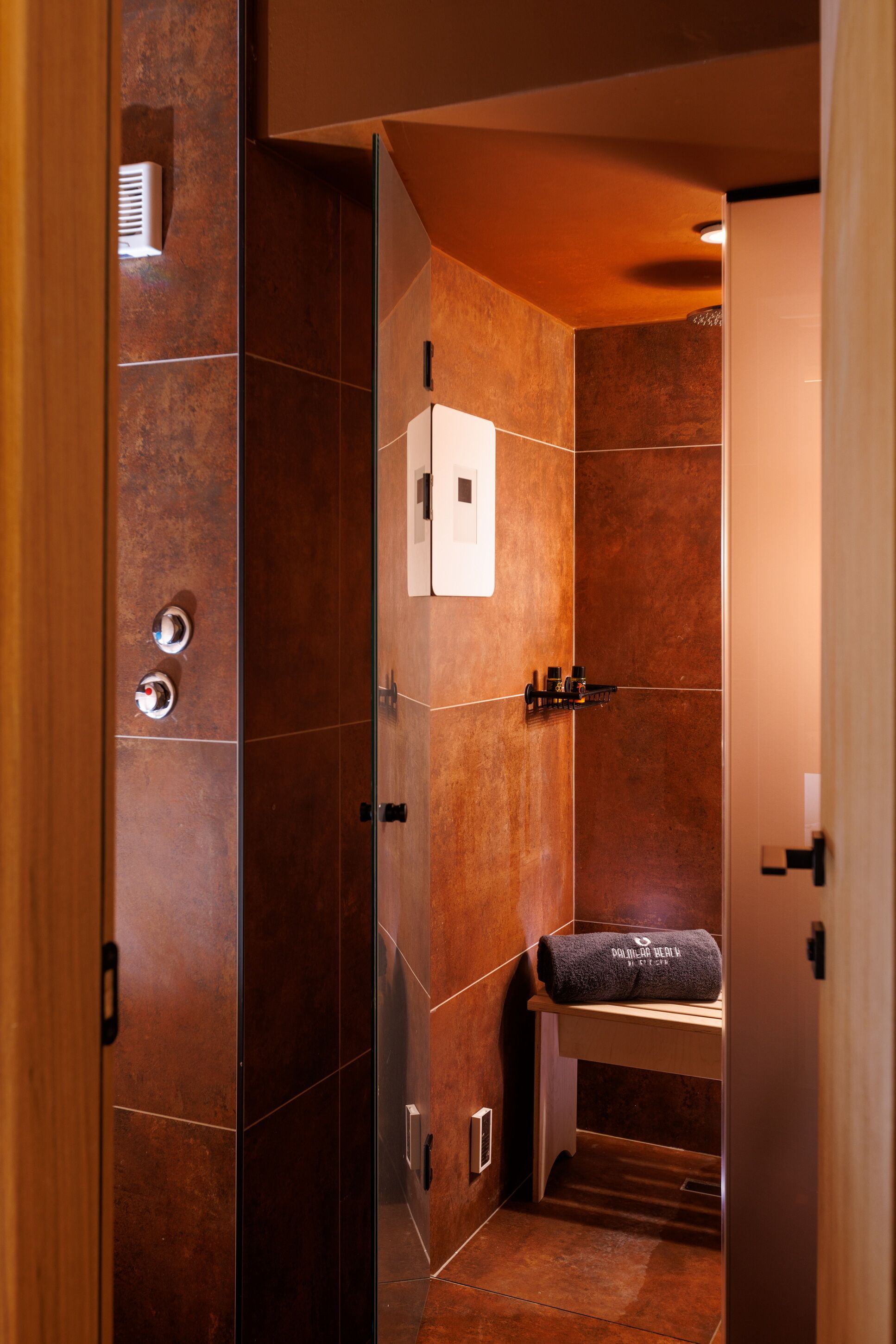 Une salle de bain moderne avec une douche à parois de verre, un porte-serviettes et un petit banc.