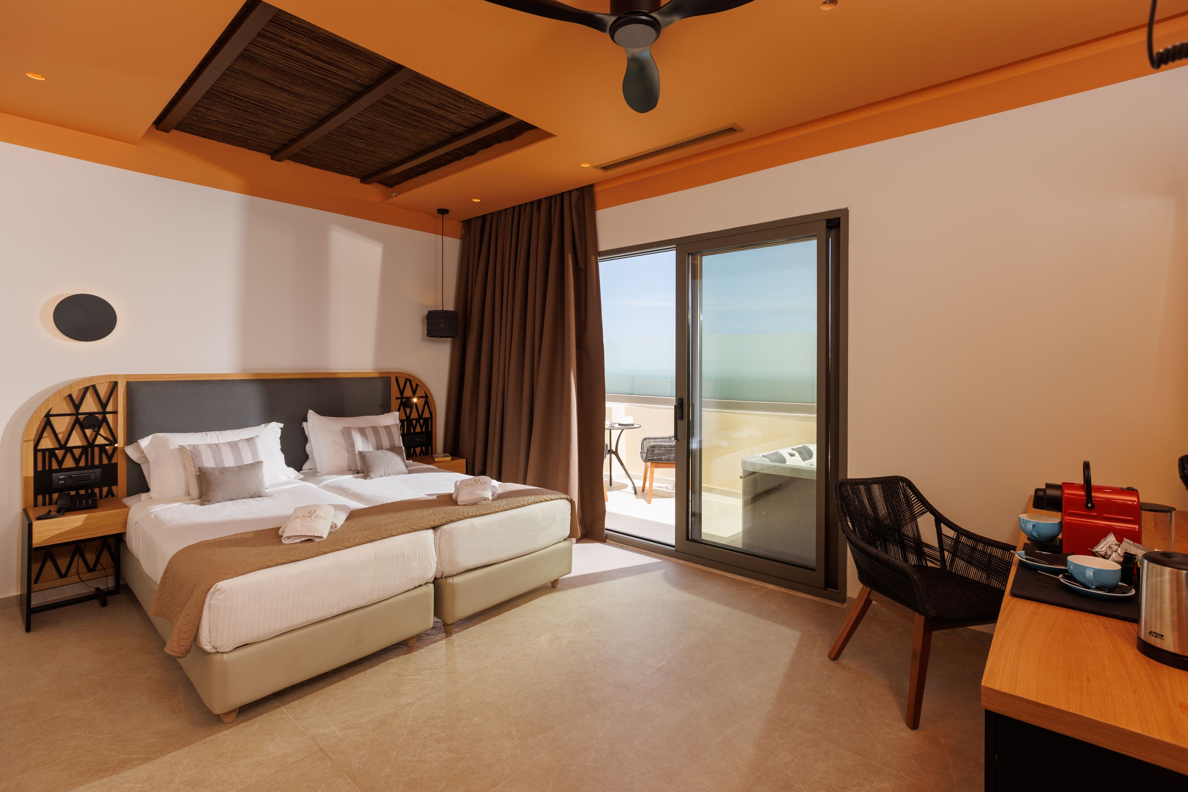 Una habitación de hotel moderna con una cama grande, un escritorio, una silla y un balcón con vistas.