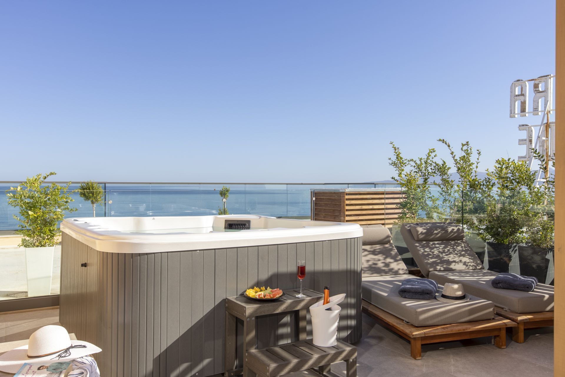 A rooftop terrace with a hot tub, lounge area, and a view of the sea.
