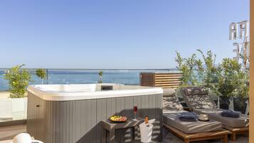A rooftop terrace with a hot tub, lounge area, and a view of the sea.