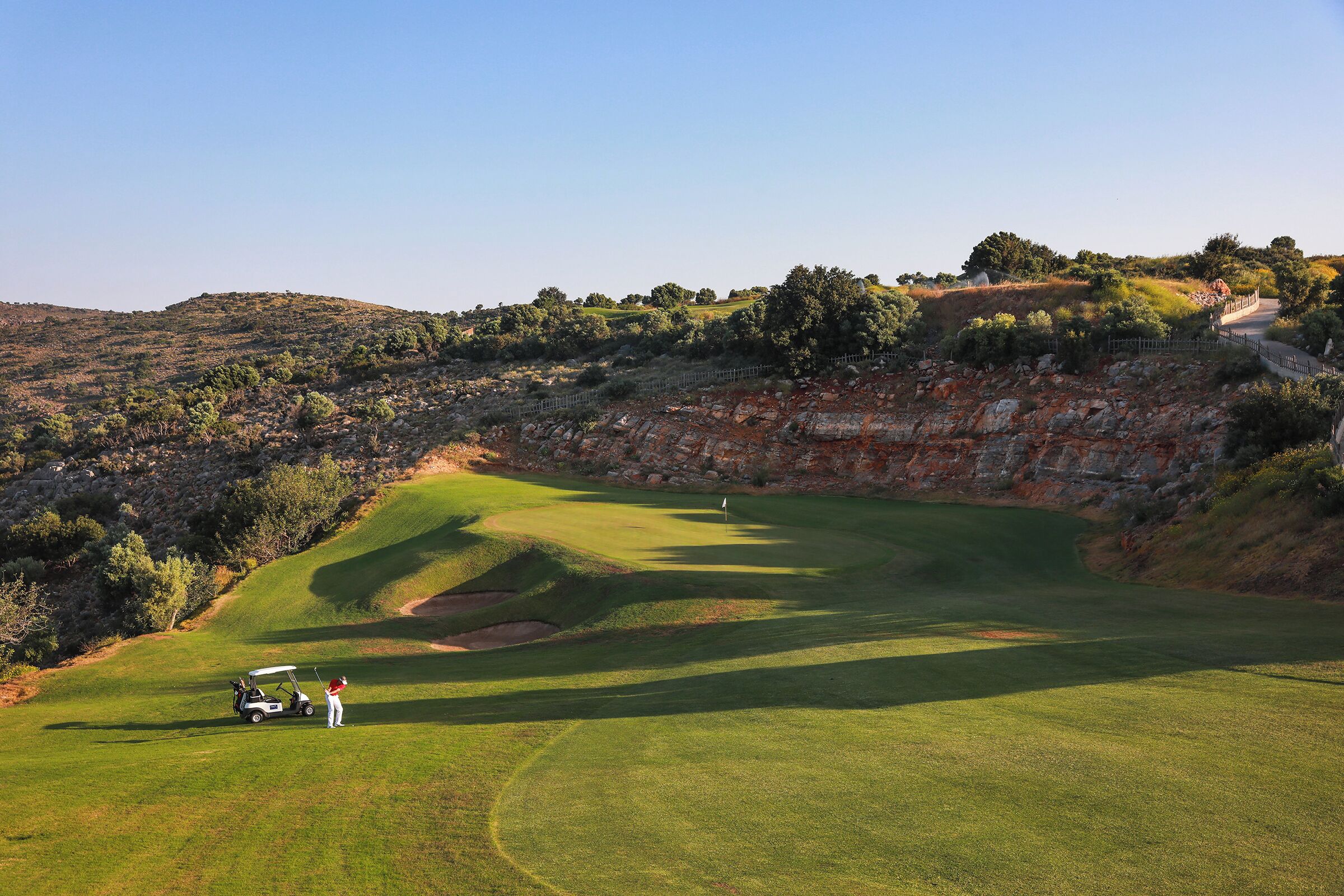 A golf course with a clear view of the green, sand bunkers, and surrounding landscape.