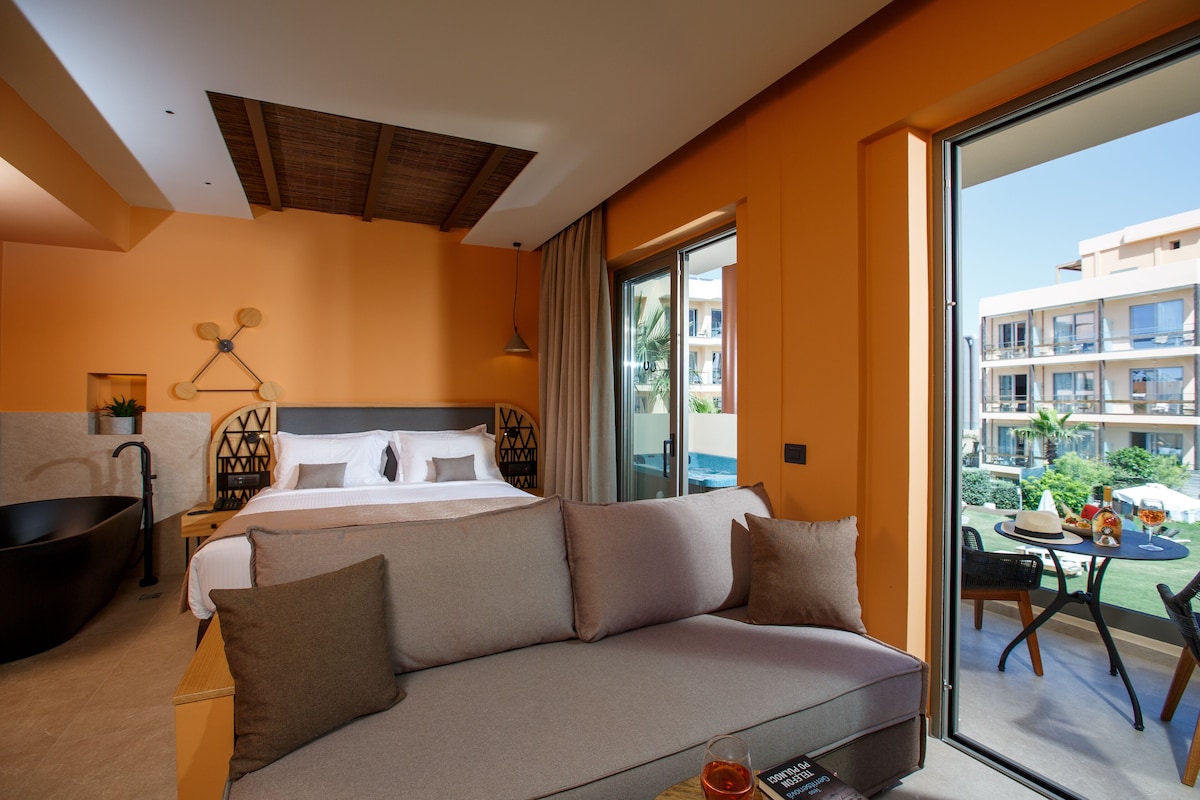 Una habitación de hotel moderna con una cama grande, un sofá, una bañera y un balcón con vistas a otros edificios.